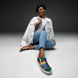 A view of someone sitting with one Rainbow Nation Women’s slip-on canvas shoes extended outward
